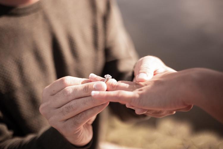 man putting engagement ring on woman's finger