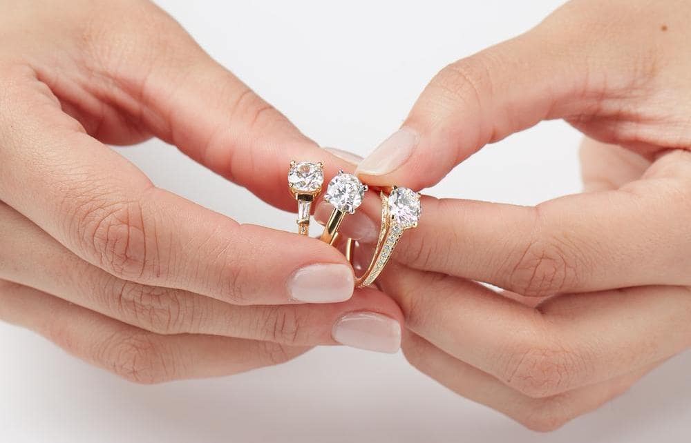 woman holding three yellow gold engagement rings