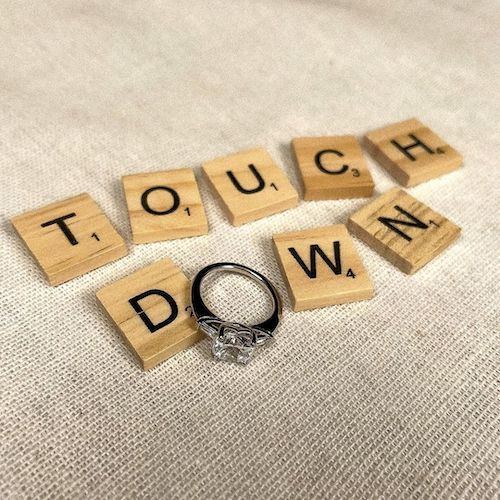 engagement ring set in scrabble letters reading "touch down"