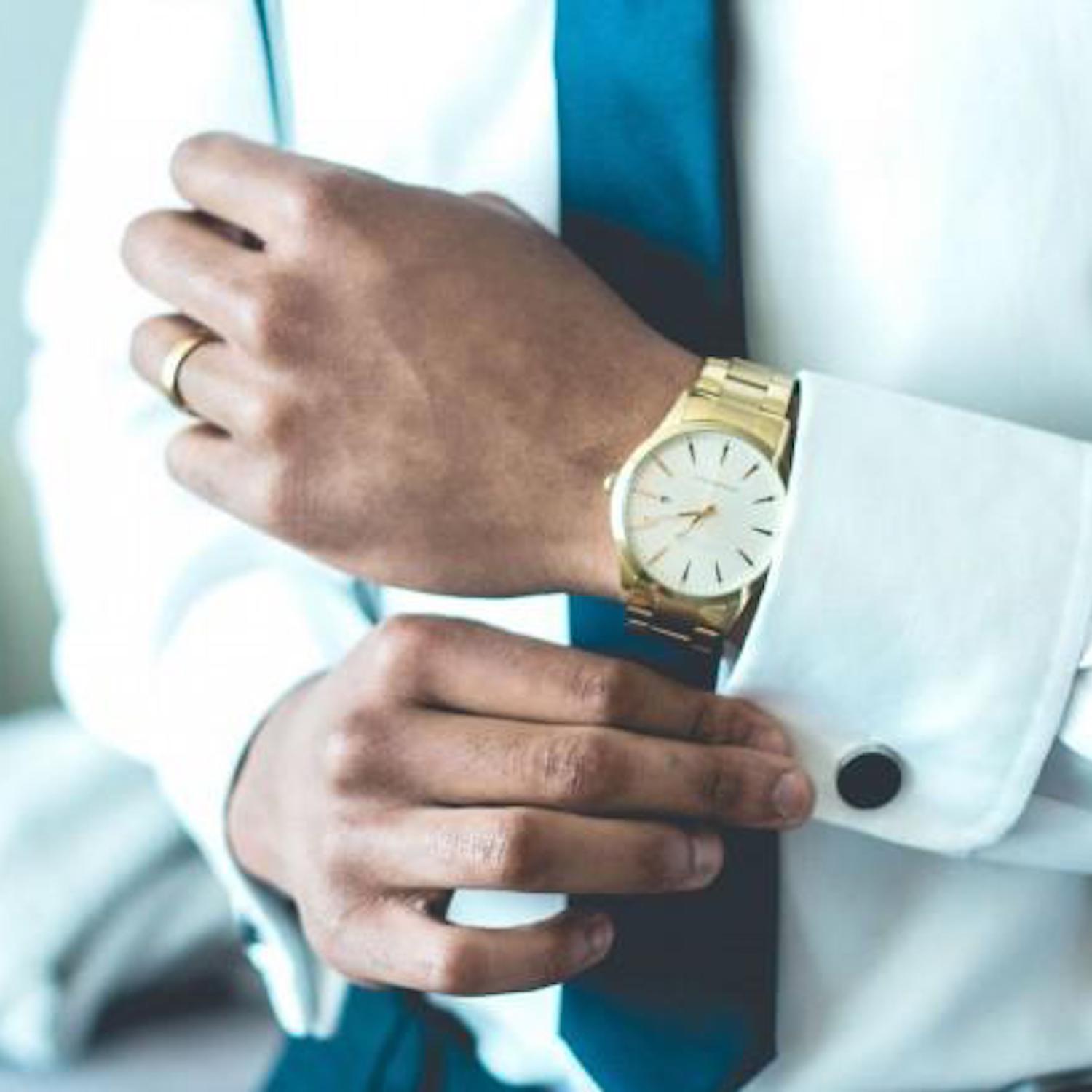 man wearing a yellow gold watch and wedding band