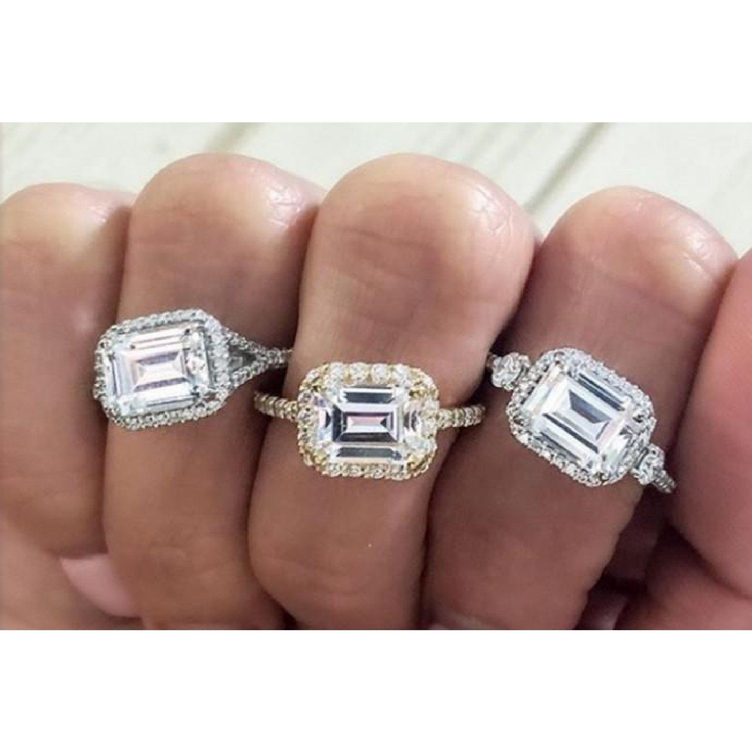 east-west set emerald cut engagement rings on hand