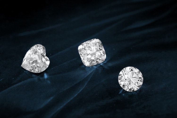 a loose heart-cut diamond, cushion-cut diamond, and round-cut diamond